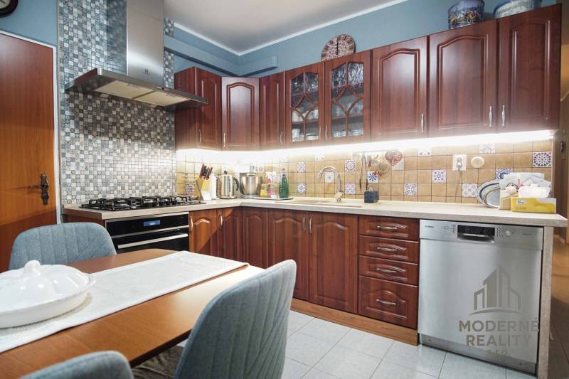 A kitchen in a 3-room apartment with wooden cabinets and a mosaic on the wall.
