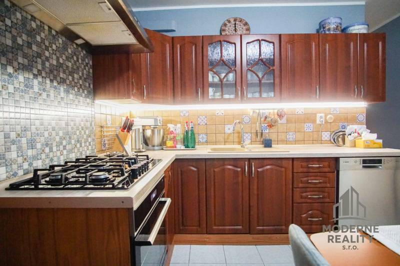 A kitchen with dark wooden cabinets and tiles in a 3-room apartment.