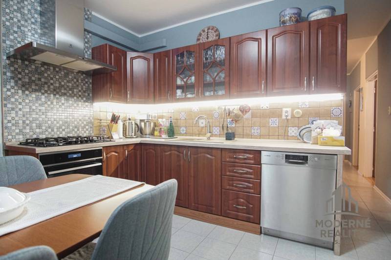 A kitchen in a 3-room apartment with dark cabinets and tiled backsplash.