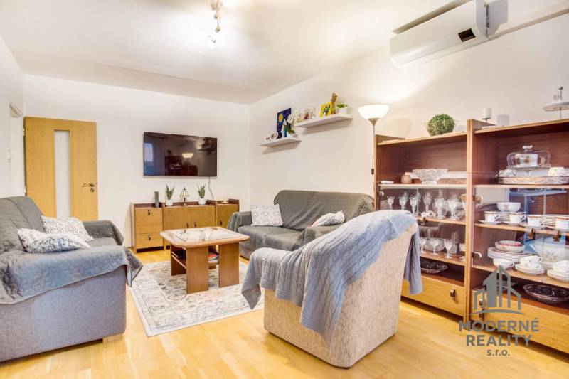 Living room in a 3-room apartment with a wooden decor floor, comfortable sofas, and a television.