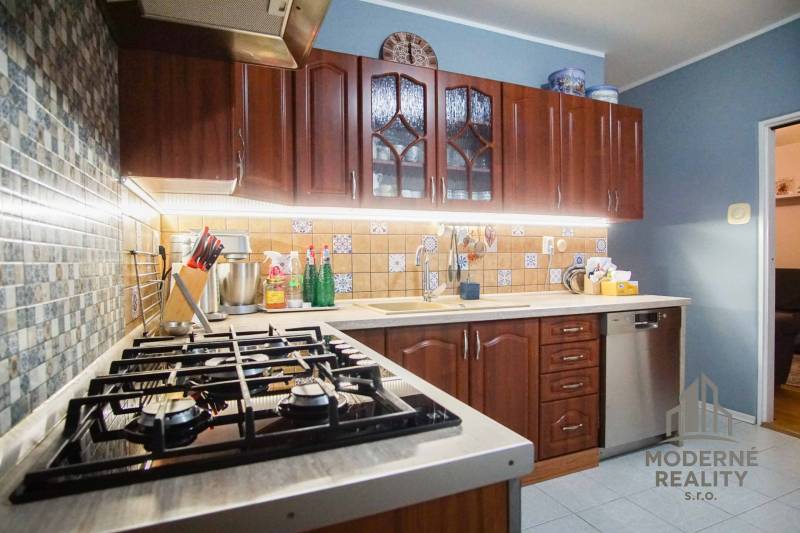 A kitchen in a 3-room apartment with wooden cabinets and patterned tiles.