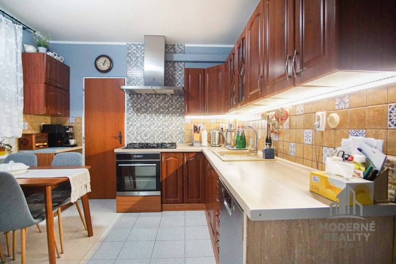 A kitchen in a 3-room apartment with wooden cabinets and a dining table.