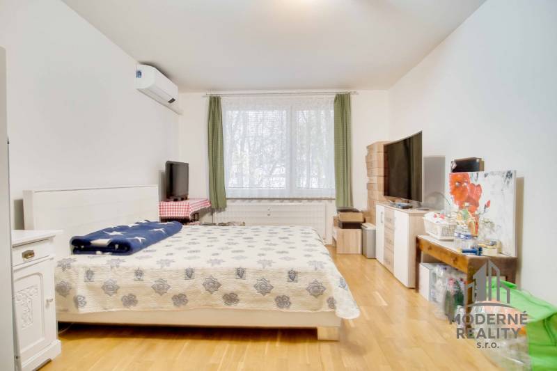 A bedroom in a 3-room apartment with light furniture and a wooden decor floor.