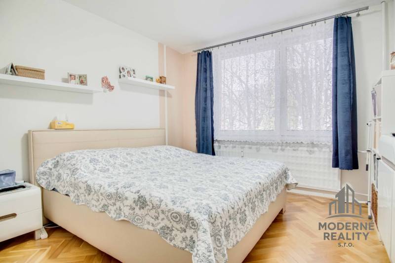 Bedroom with a bed, shelves, and a window in a 3-room apartment, floor with wooden decor.