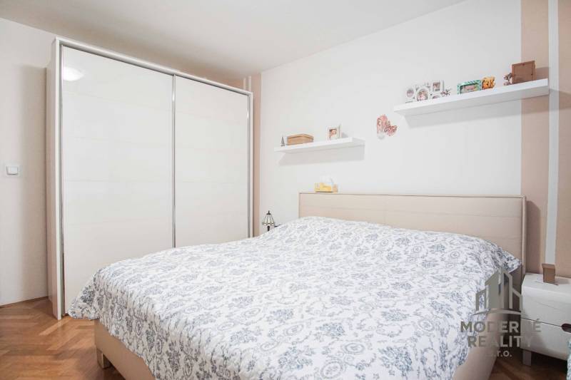 A bedroom in a 3-room apartment with a wooden decor floor, a double bed, and a built-in wardrobe.