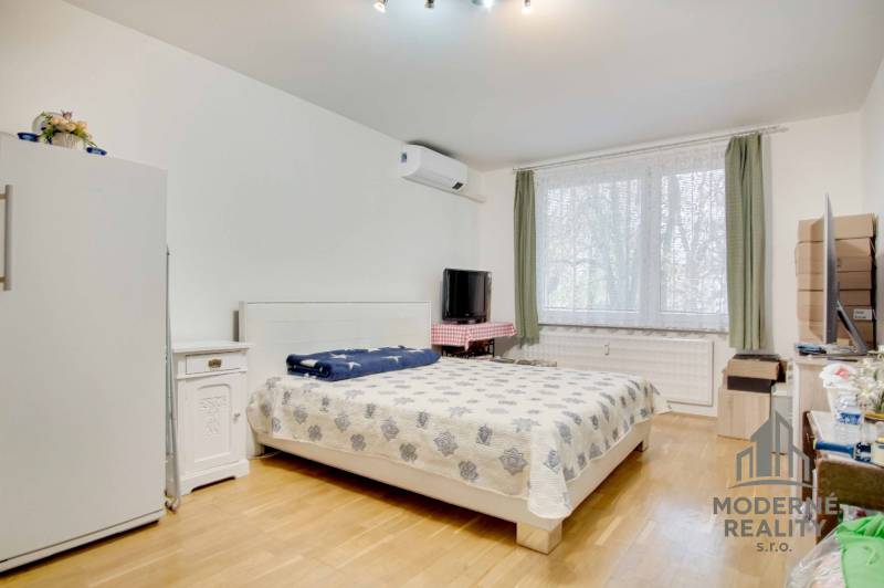 Bedroom in a 3-room apartment with a bed, window, wardrobe, and floor with wooden decor.
