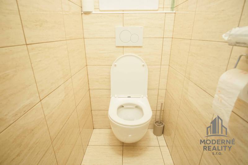 A toilet in a 3-room apartment with beige tiles and a clean design.