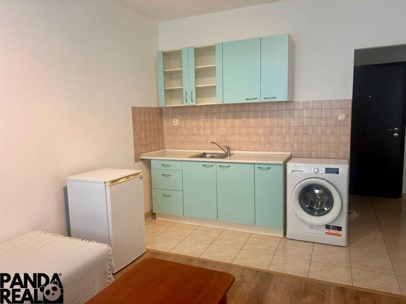 Studio apartment with kitchenette, washing machine, and refrigerator; floor with wood decor.