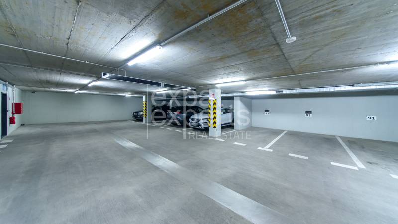 Underground parking space in garages, well-lit, with marked parking spots.