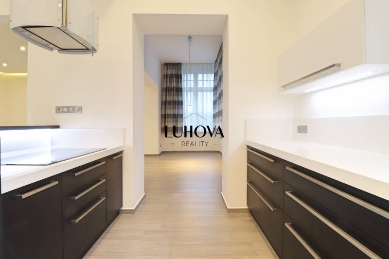 A kitchen in a 3-room apartment with a wooden decor floor and built-in appliances.