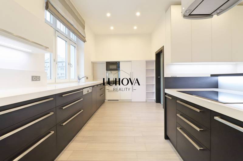 A kitchen in a 3-room apartment with a wooden decor floor and white cabinets.
