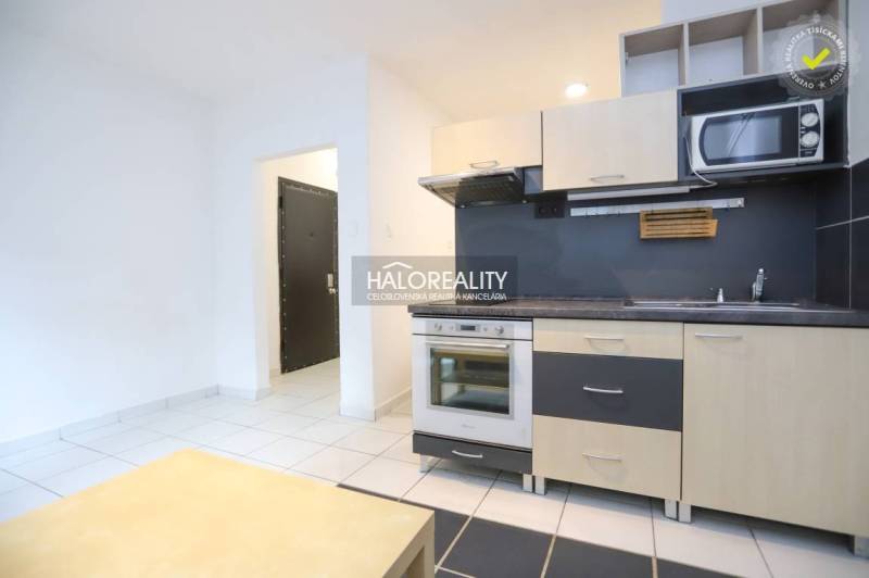 A simple kitchen in a studio apartment with white and black flooring.