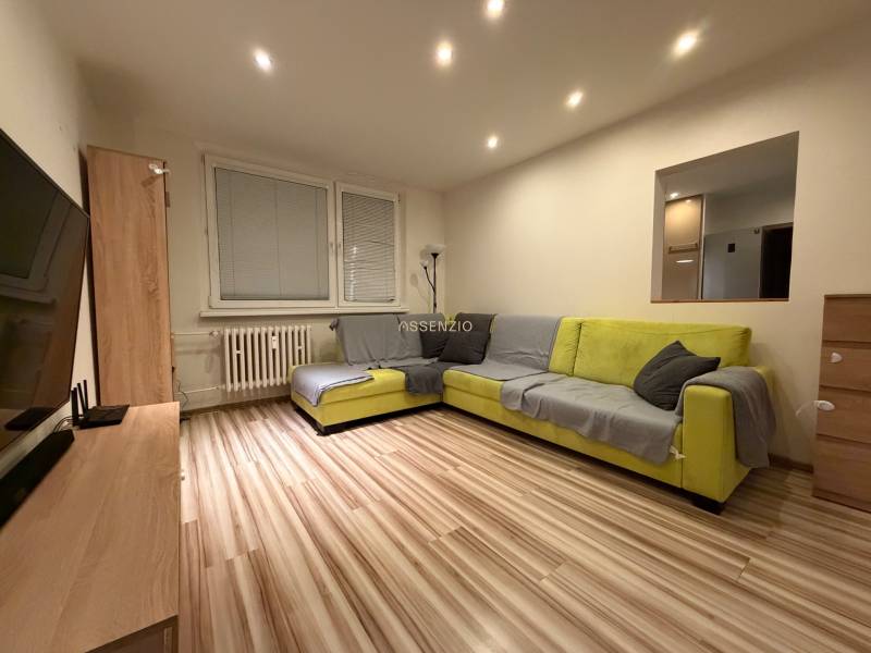 Living room in a 3-room apartment with a corner sofa and a wooden decor floor.