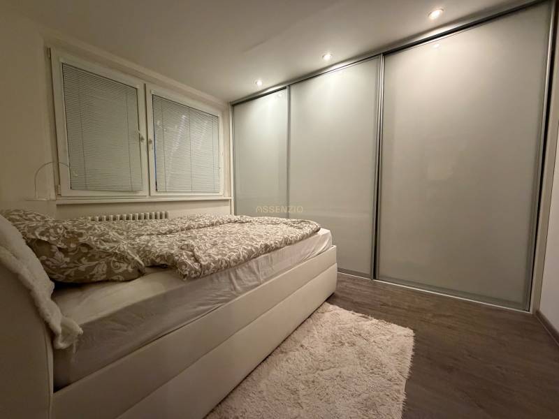 A bedroom in a 3-room apartment with a bed, built-in wardrobe, and floor with a wooden decor.