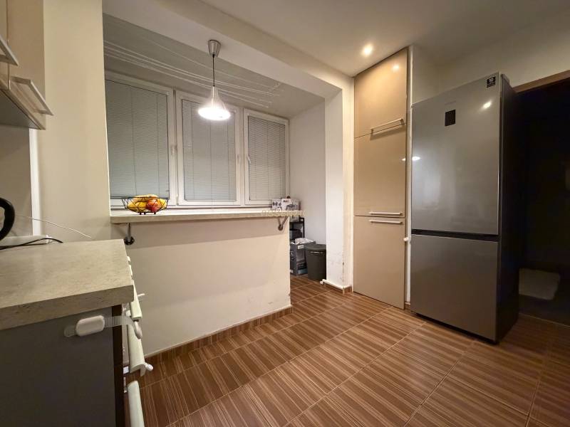 A kitchen in a 3-room apartment with a refrigerator, a cabinet, and a floor with a wooden decor.