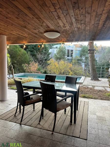 A terrace with seating by the pool, surrounded by trees on Dolná Street, Bratislava - Staré Mesto.