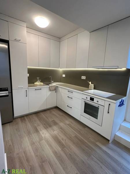 A kitchen in a 3-room apartment with built-in appliances and a floor with a wooden decor.