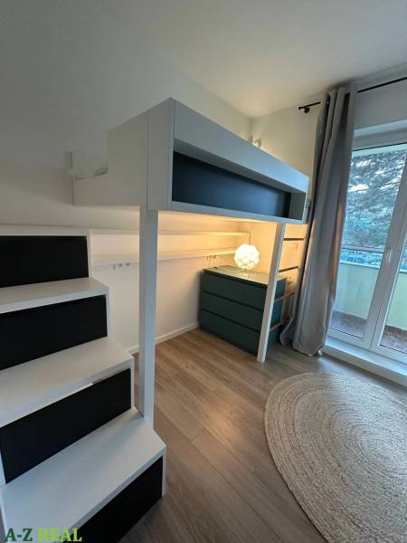 Interior of a 3-room apartment with a raised bed, wooden decor flooring, and a terrace.