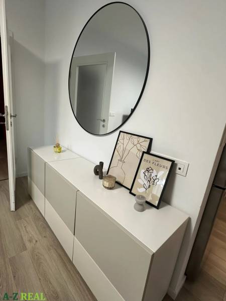 A modern sideboard with decorations and a round mirror in a 3-room apartment.