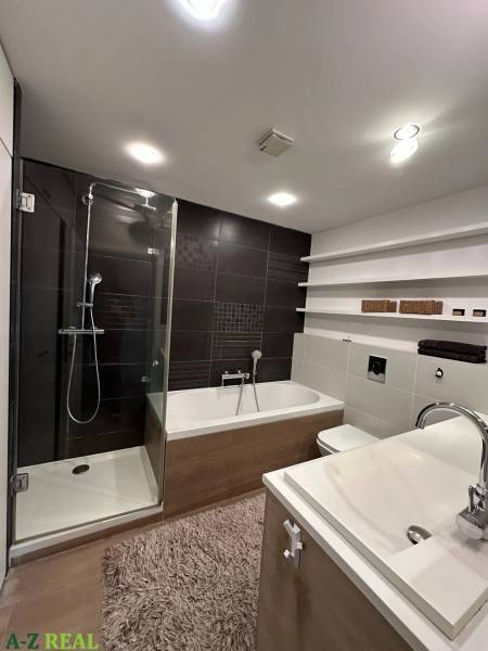Bathroom with a bathtub, shower, and sink in a 3-room apartment, floor with a wooden decor.