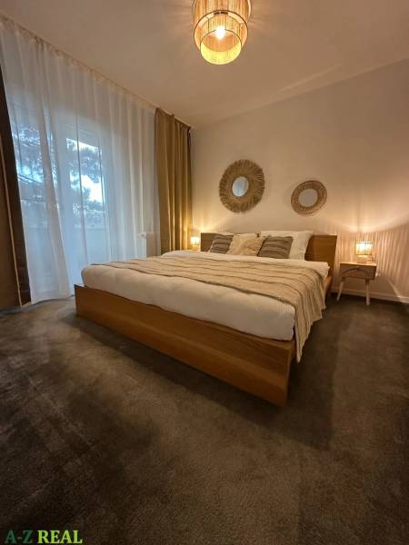 Bedroom in a 3-room apartment with carpet flooring and natural decorations.