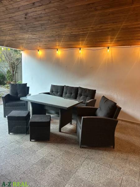 Covered terrace with rattan seating and string lights in a 3-room apartment.