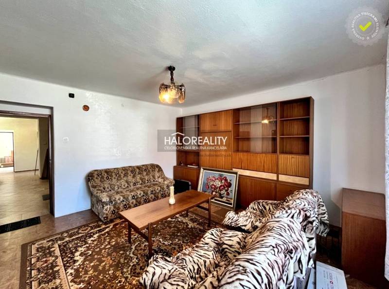 Living room in a family house with a sofa set, wooden wall, and carpet.