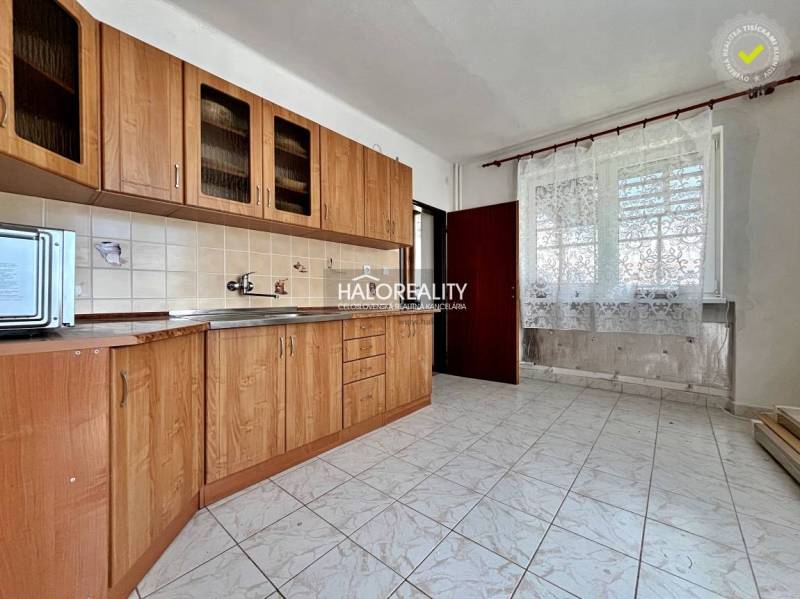 A kitchen with light tiles, wooden cabinets, and ceramic tiles in a family house.