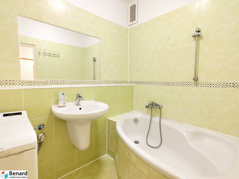 Bathroom in a 3-room apartment, light green tiles, bathtub, sink, mirror, washing machine.