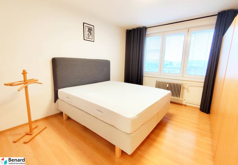 A bedroom with a bed, black curtain, and wood-patterned flooring in a 3-room apartment.