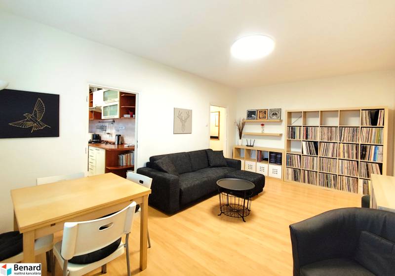 Living room in a 3-room apartment with a sofa, dining table, and a shelf for records.