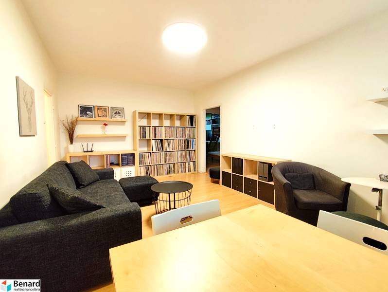 Living room in a 3-room apartment with a sofa, armchairs, shelves, and a wooden decor floor.