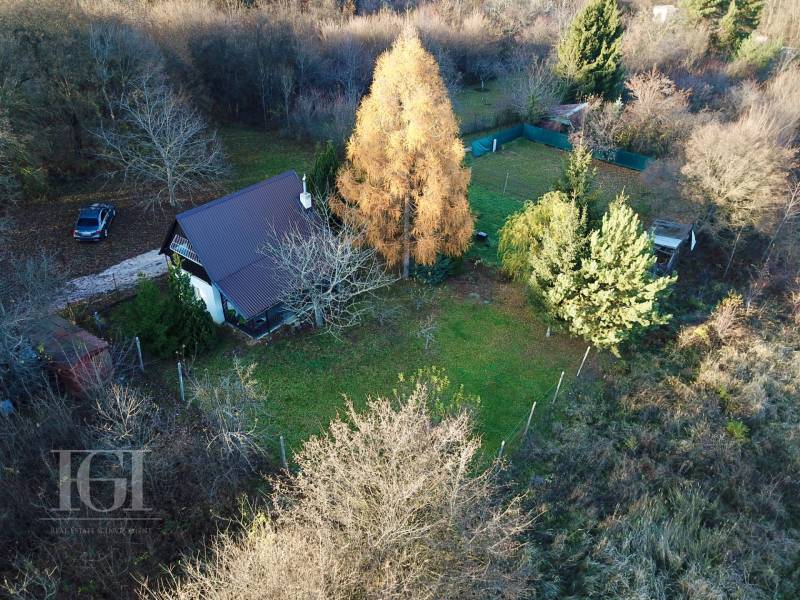 A cottage in Štitáre surrounded by greenery and trees, with a car on the driveway.