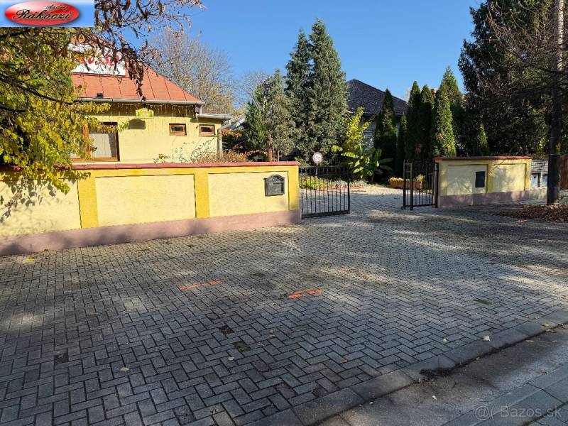 Commercial premises on Park Street and the main road in Veľké Ludince with a gate and trees.