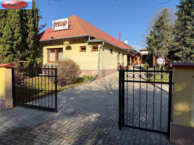 Courtyard with a gate, café, and building with commercial spaces in Veľké Ludince.