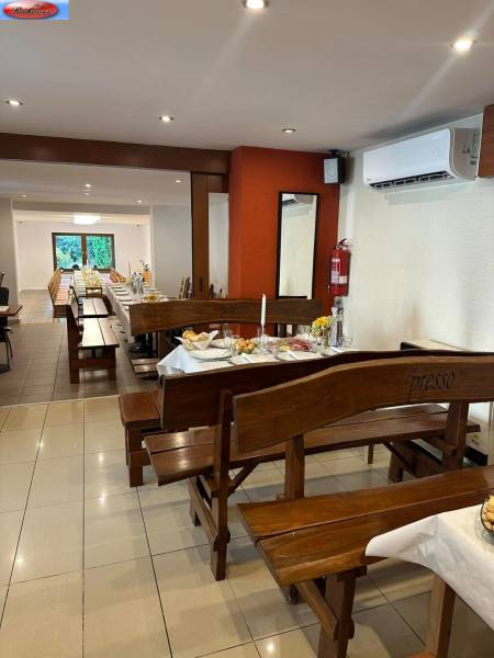Interior of commercial premises with wooden benches, set tables, and air conditioning.