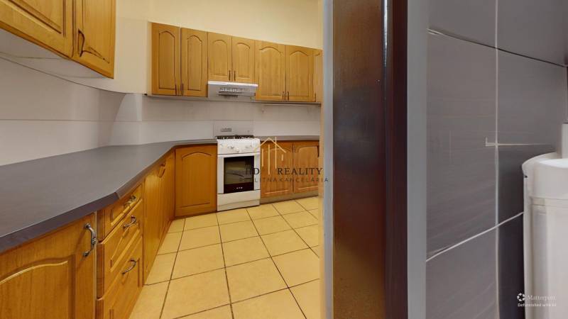 A kitchen in a family house with wooden cabinets and a tiled floor.