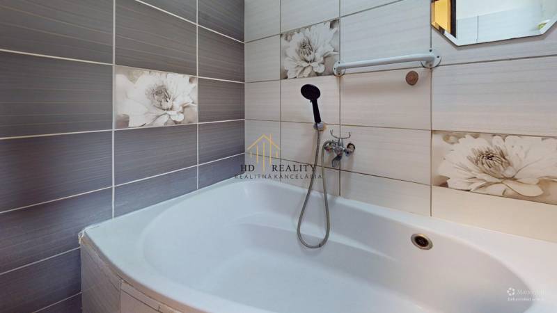 A bathroom in a family house with floral tiles and a bathtub.