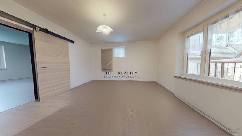 The interior of a room in a family house with a wood-patterned floor and a glass window.