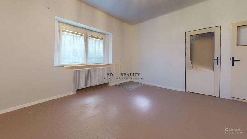 White wall, window with radiator, and door in a room in a family house.