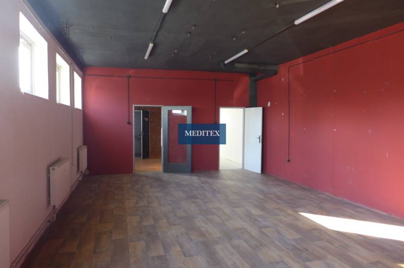 Red walls, wood-patterned floor, and windows in an industrial space of warehouses and halls.