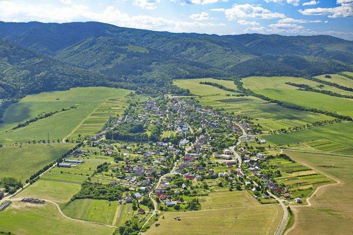 Aerial view of agricultural and forest land around Hertník surrounded by forests.