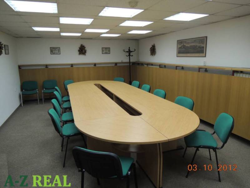 A conference room with a long wooden table and green chairs in an office.