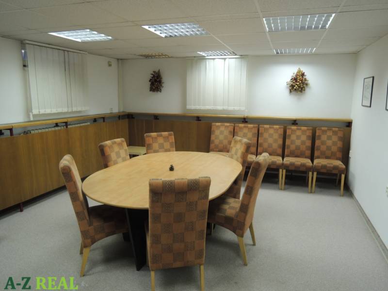 Offices with an oval table and patterned chairs on a carpet.