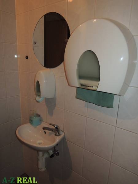 Offices with a sink, a round mirror, and a paper towel dispenser.