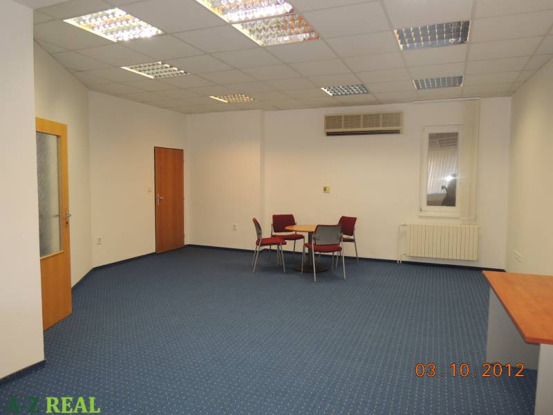 Offices with blue carpet, ceiling lights, desks, and chairs.