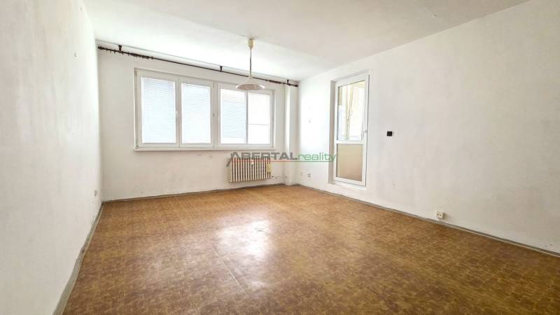 A room with a wooden floor, white walls, and a large window.
