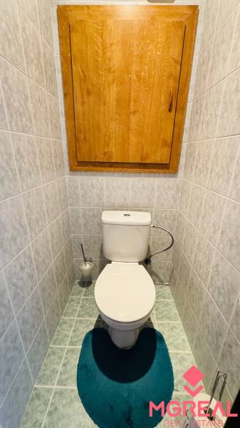 Bathroom in a 4-room apartment with gray tiles and a green carpet.
