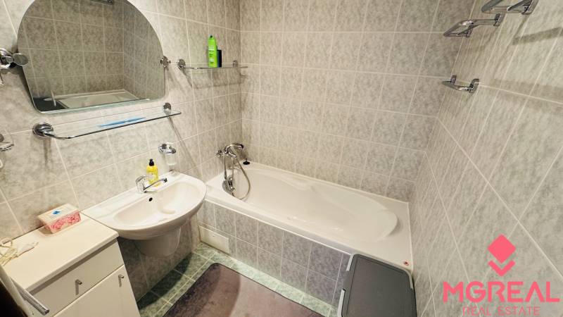 A bathroom with a bathtub and a sink in a 4-room apartment, tiles in light tones.