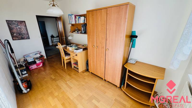 A room with a wooden floor decor, a desk, and a wardrobe in a 4-room apartment.